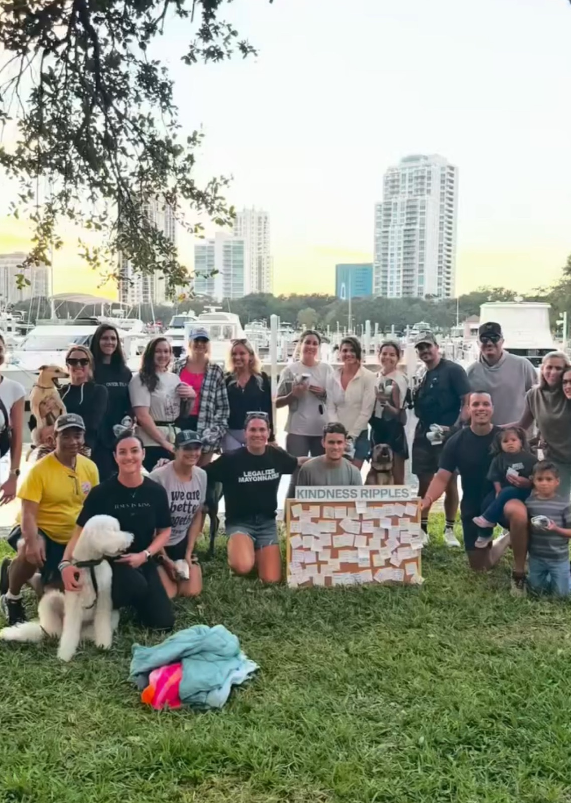 A group of volunteers gathered at sunset by the St. Pete marina with a Kindness Ripples board full of notes